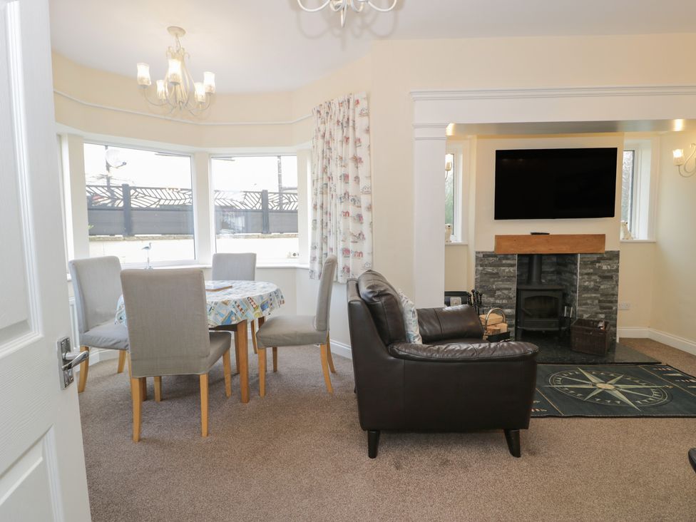 A dining room with a table and chairs and a fireplace at Roma in Rhos-on-Sea