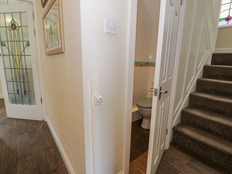 A hallway with a staircase and a toilet door at Roma in Rhos-on-Sea