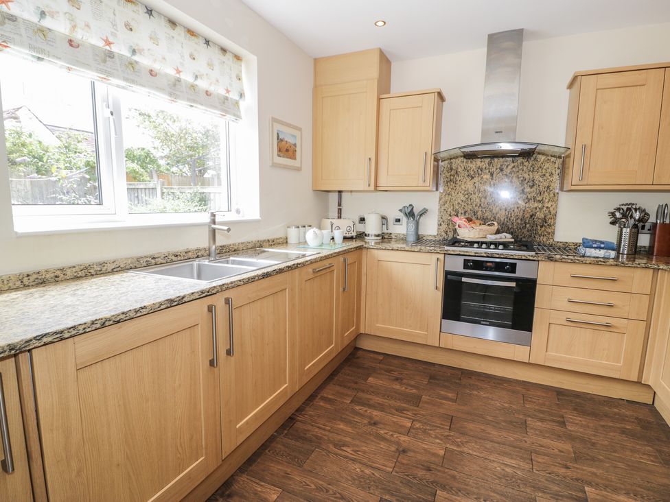 A kitchen with wooden cabinets and modern appliances at Roma in Rhos-on-Sea