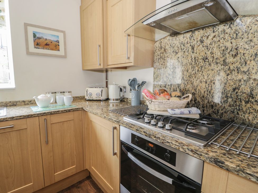 A kitchen with cabinets, stove, oven, sink, and utensils at Roma in Rhos-on-Sea
