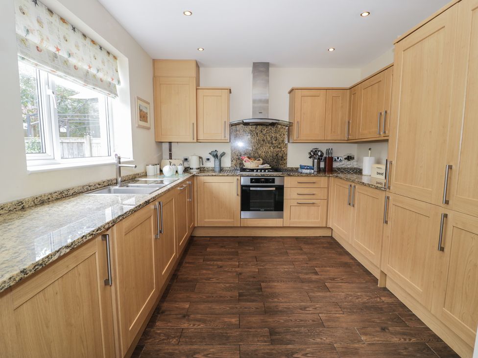 A kitchen with wooden cabinets and granite countertops at Roma in Rhos-on-Sea