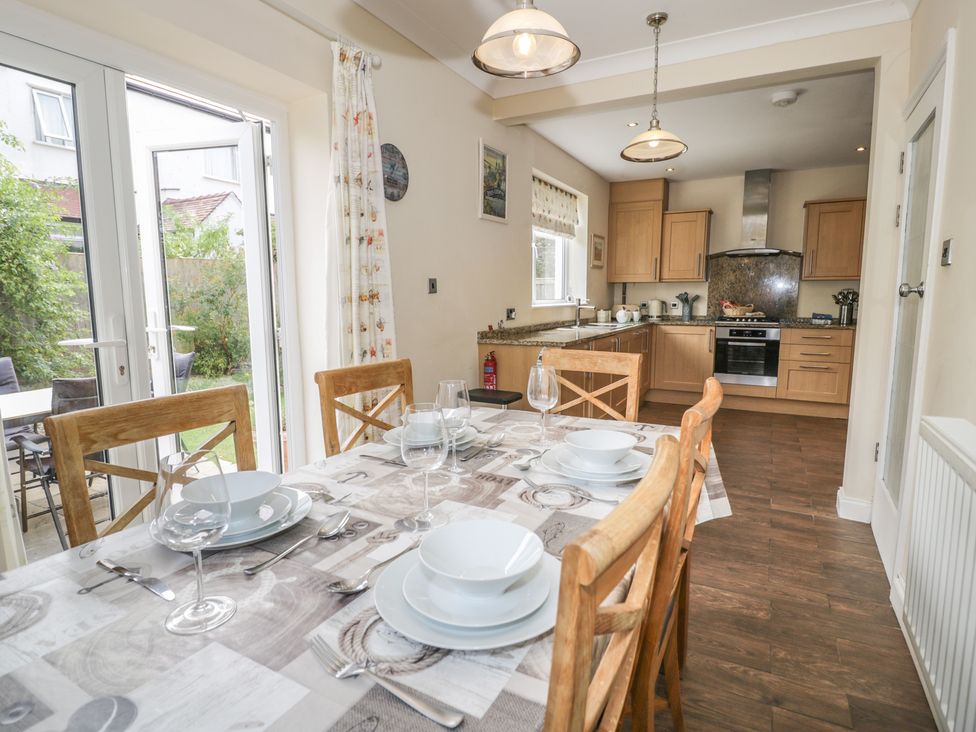 A dining room with a table set for meals and a kitchen in Roma Rhos-on-Sea