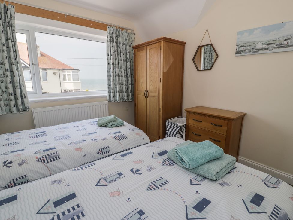 A bedroom with two beds and a wardrobe at Roma in Rhos-on-Sea