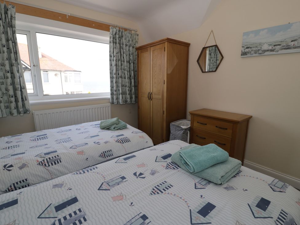 A bedroom with two beds and a wardrobe at Roma in Rhos-on-Sea