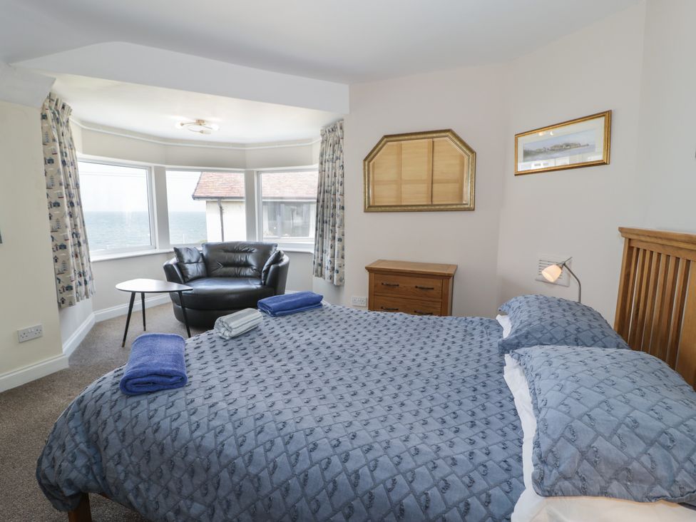 A bedroom with a bed and armchair at Roma in Rhos-on-Sea