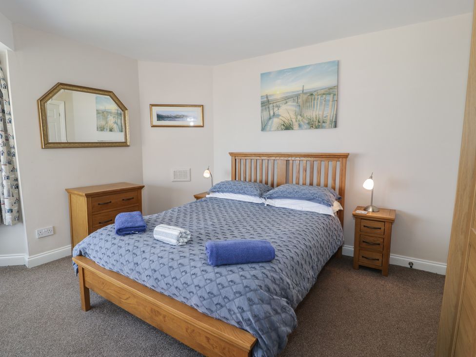 A bedroom with a bed, nightstand, and mirror at Roma in Rhos-on-Sea