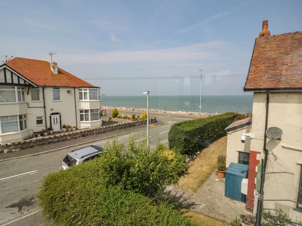 A view of a seaside road with houses and the sea at Roma in Rhos-on-Sea