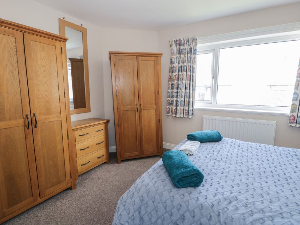 A bedroom with wardrobes and a mirror at Roma in Rhos-on-Sea