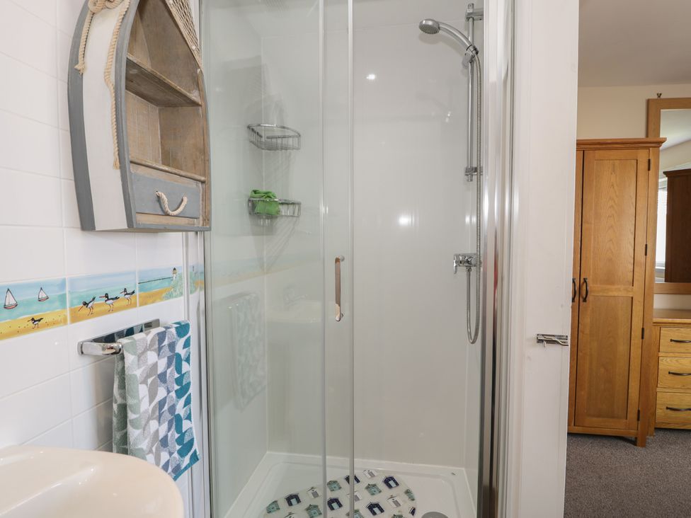 A bathroom with a shower enclosure and storage at Roma in Rhos-on-Sea