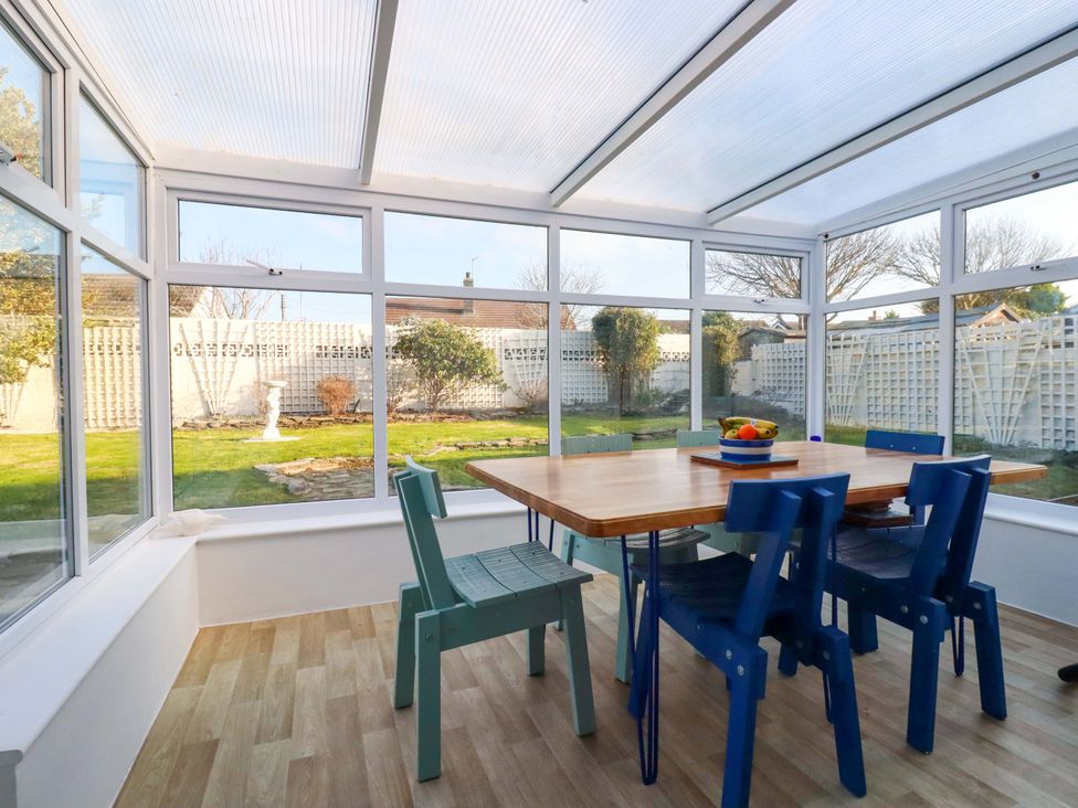 A conservatory with a table and chairs at Merlin's Retreat in Tintagel
