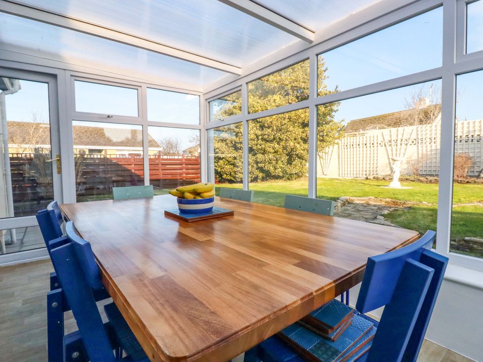 A conservatory with a wooden table and chairs at Merlin's Retreat in Tintagel