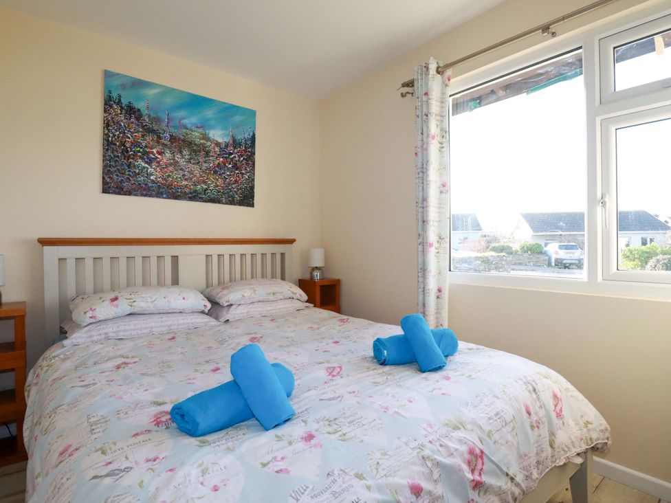 A bedroom with a bed and painting at Merlin's Retreat in Tintagel