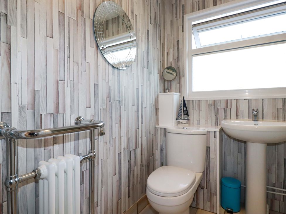 A bathroom with a toilet, sink, and mirror at Merlin's Retreat in Tintagel