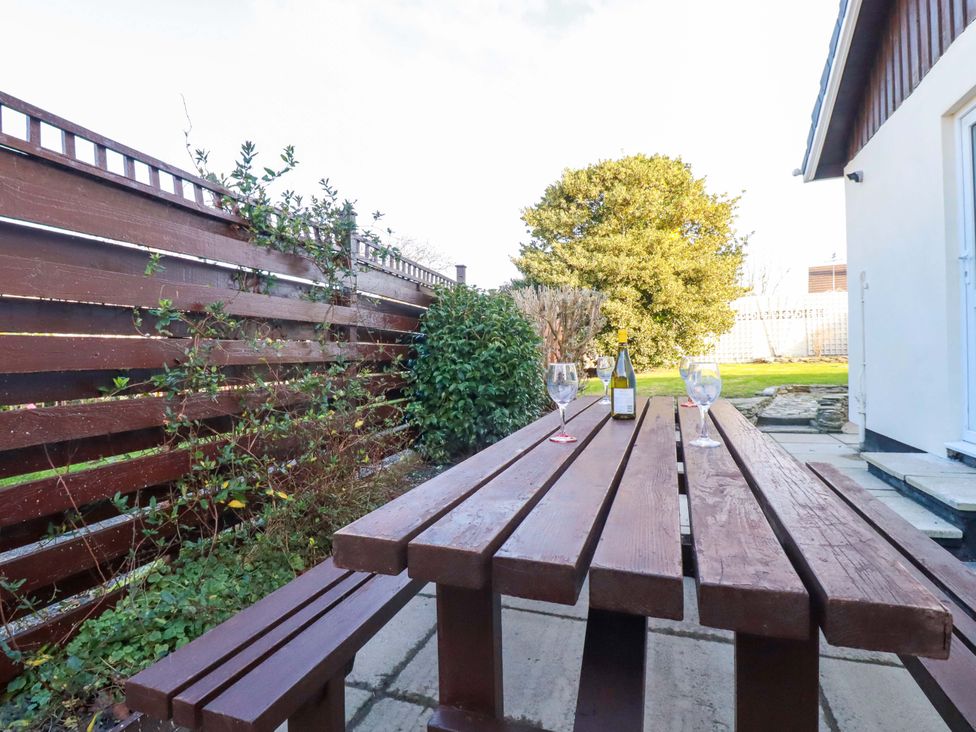 A garden with a wooden table and glasses at Merlin's Retreat in Tintagel