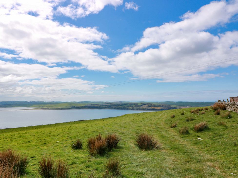 A grassy area overlooking a body of water and hills at Little Laight near Cairnryan