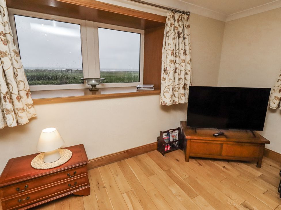A living room with a television and lamp at Long Cart Cottage in Embleton