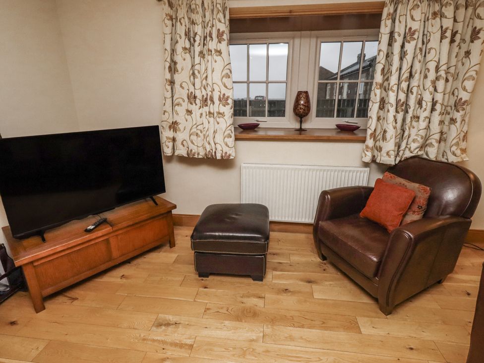 A living room with a television and armchair at Long Cart Cottage in Embleton