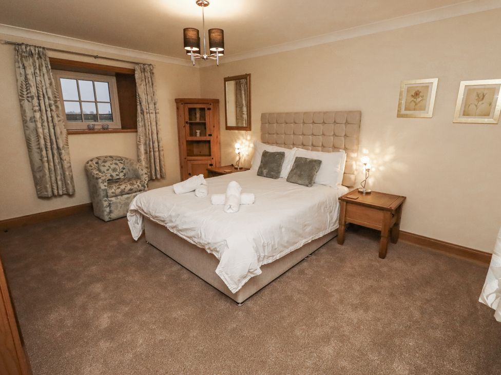 A bedroom with a bed and armchair at Long Cart Cottage in Embleton