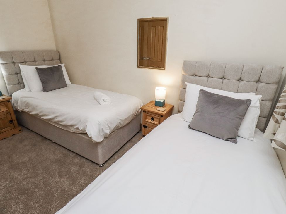 A bedroom with two single beds and a nightstand at Long Cart Cottage in Embleton