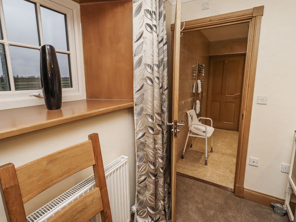 A bathroom view with a chair and towel rack at Long Cart Cottage in Embleton