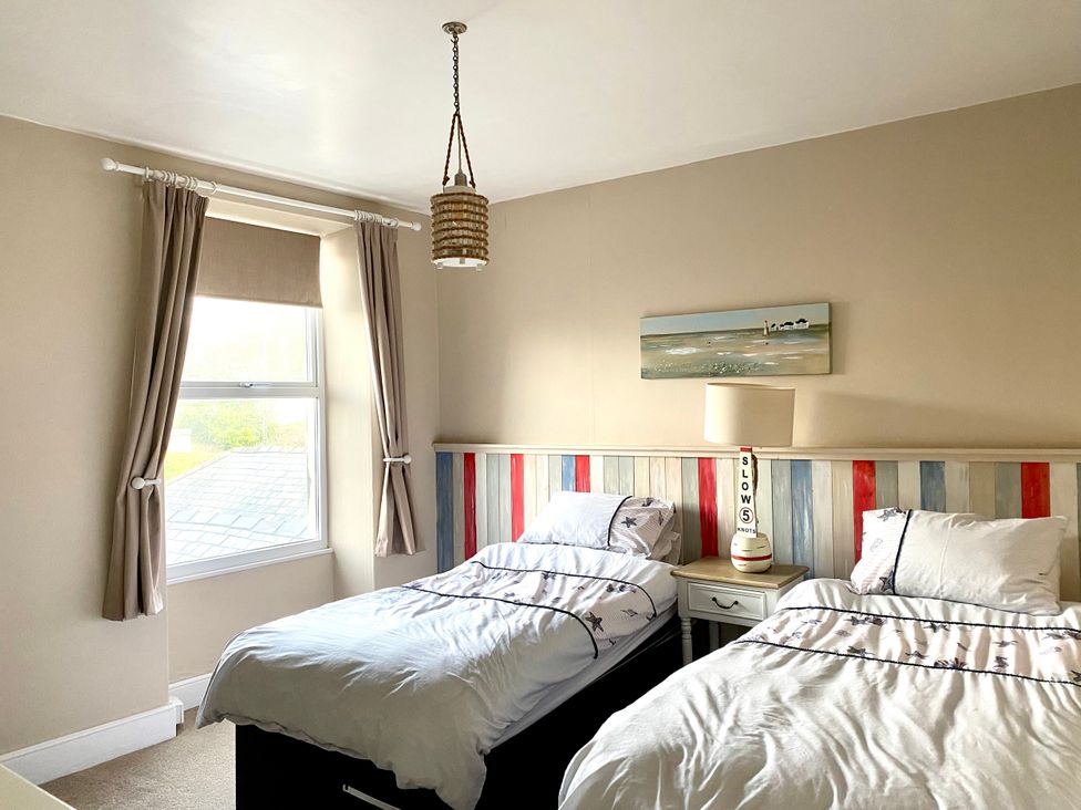 A bedroom with two beds and a bedside lamp at The View in Criccieth