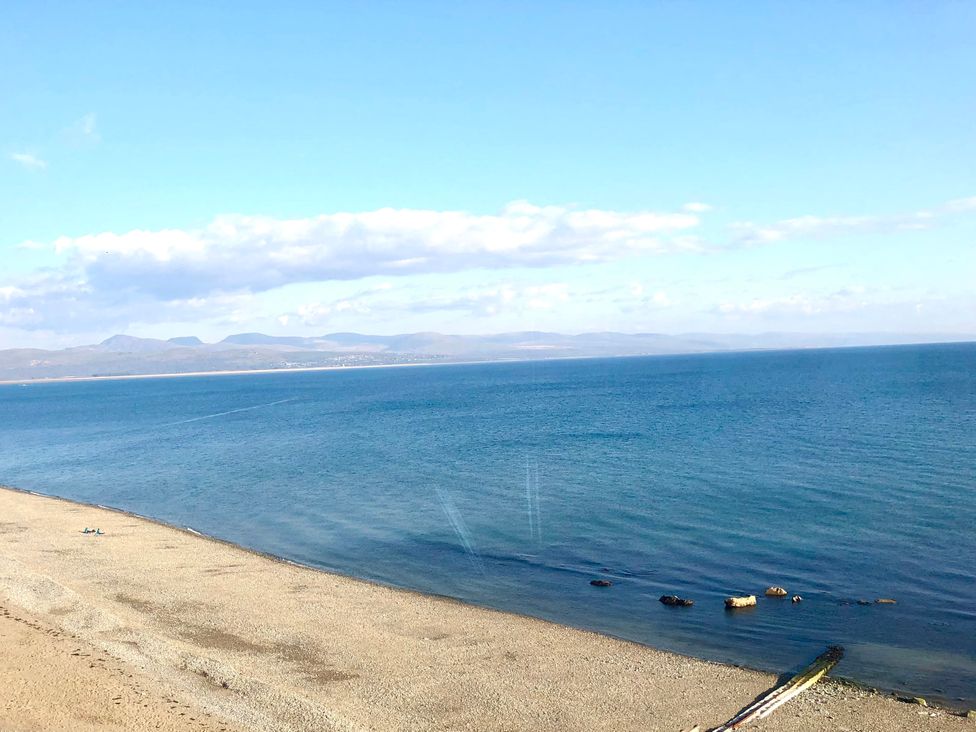 A beach view with water and mountains in the distance at The View Criccieth