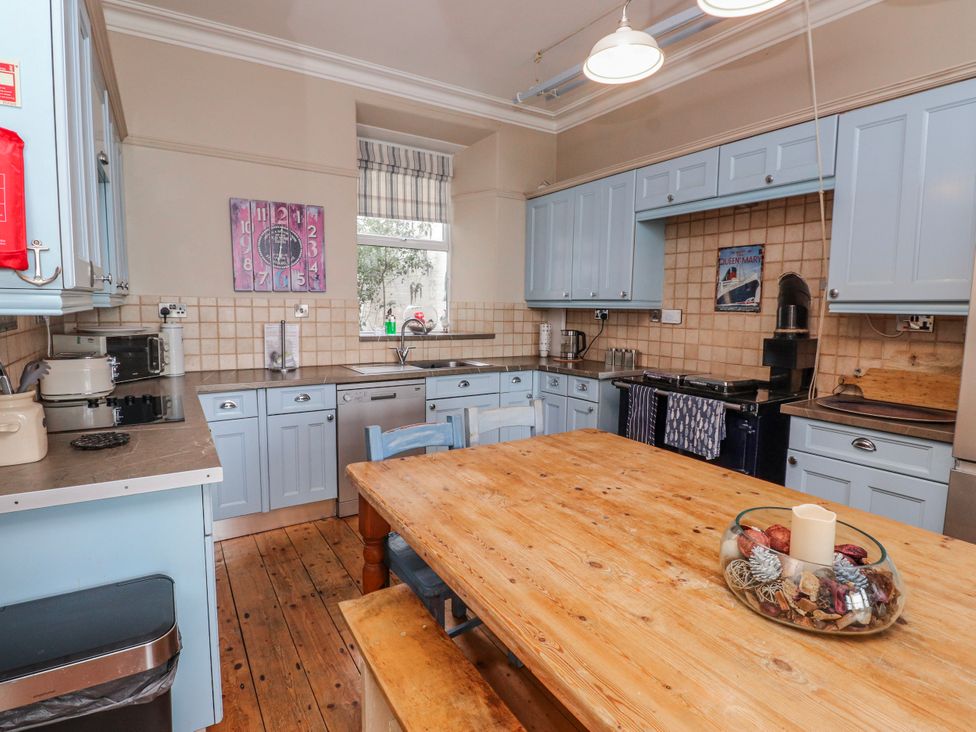 A kitchen with blue cabinets and wooden table at The View in Criccieth