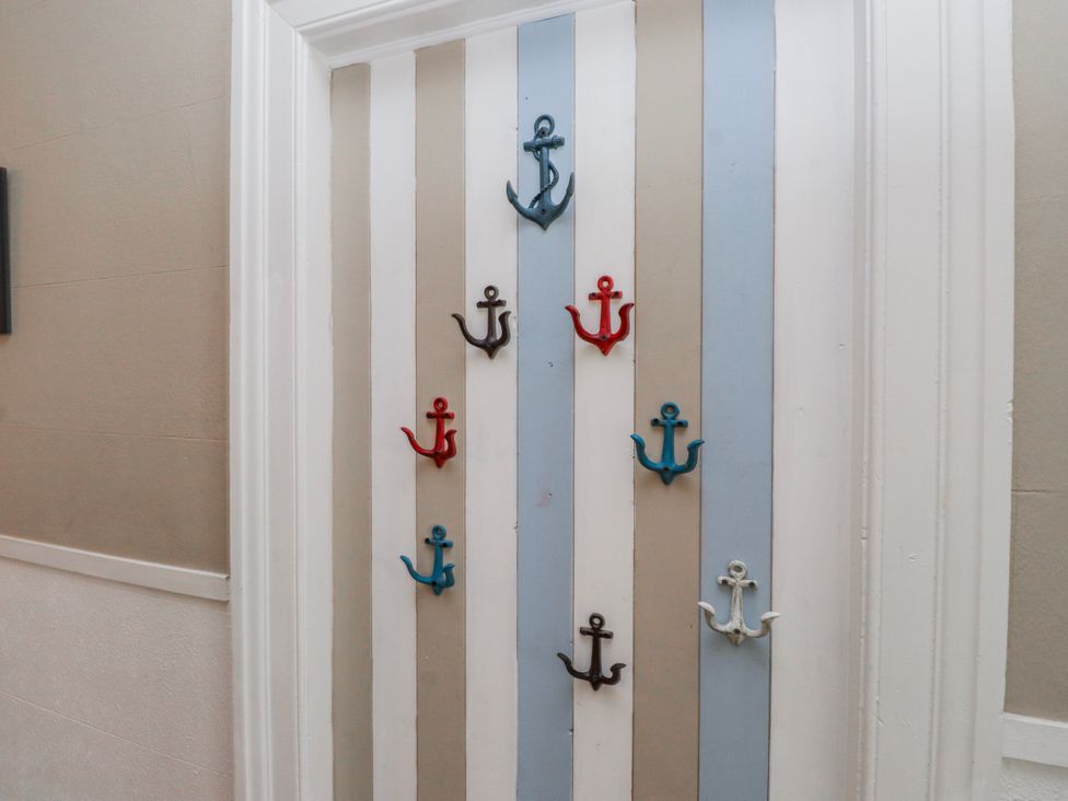 A hallway with anchor hooks on a striped door at The View in Criccieth