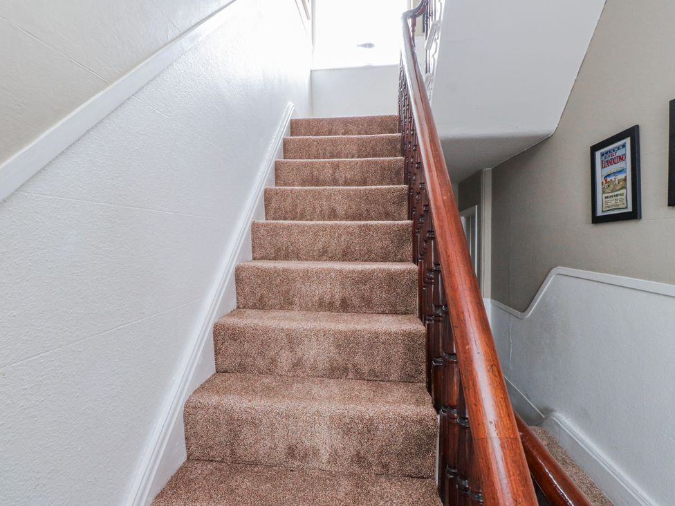 A staircase with carpeted steps and a wooden handrail at The View in Criccieth