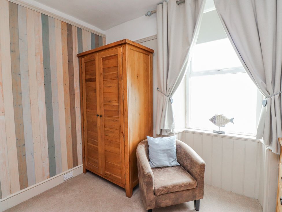 A bedroom with a wardrobe and armchair at The View in Criccieth