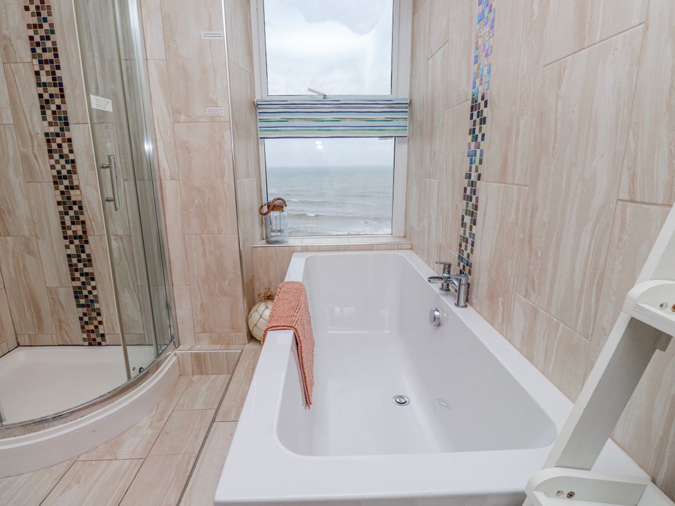 A bathroom with a bathtub and shower overlooking the sea at The View in Criccieth