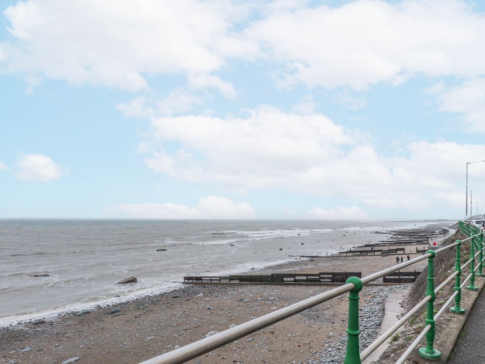 A beach with a railing and cloudy sky at The View in Criccieth
