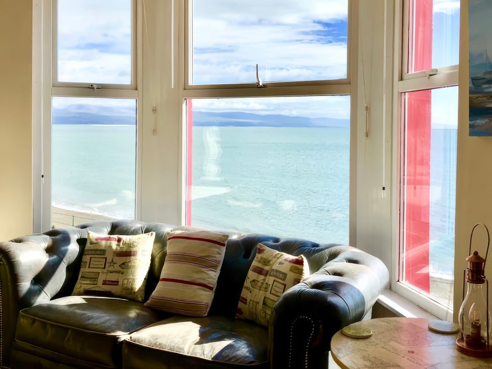 A living room with a sofa and pillows overlooking the sea at The View in Criccieth