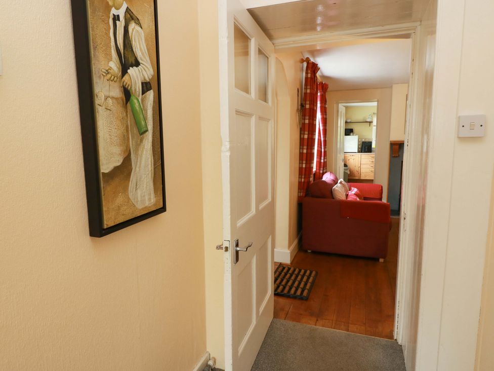 A hallway leading to a living area with a red sofa at Camphill in Kirkcudbright