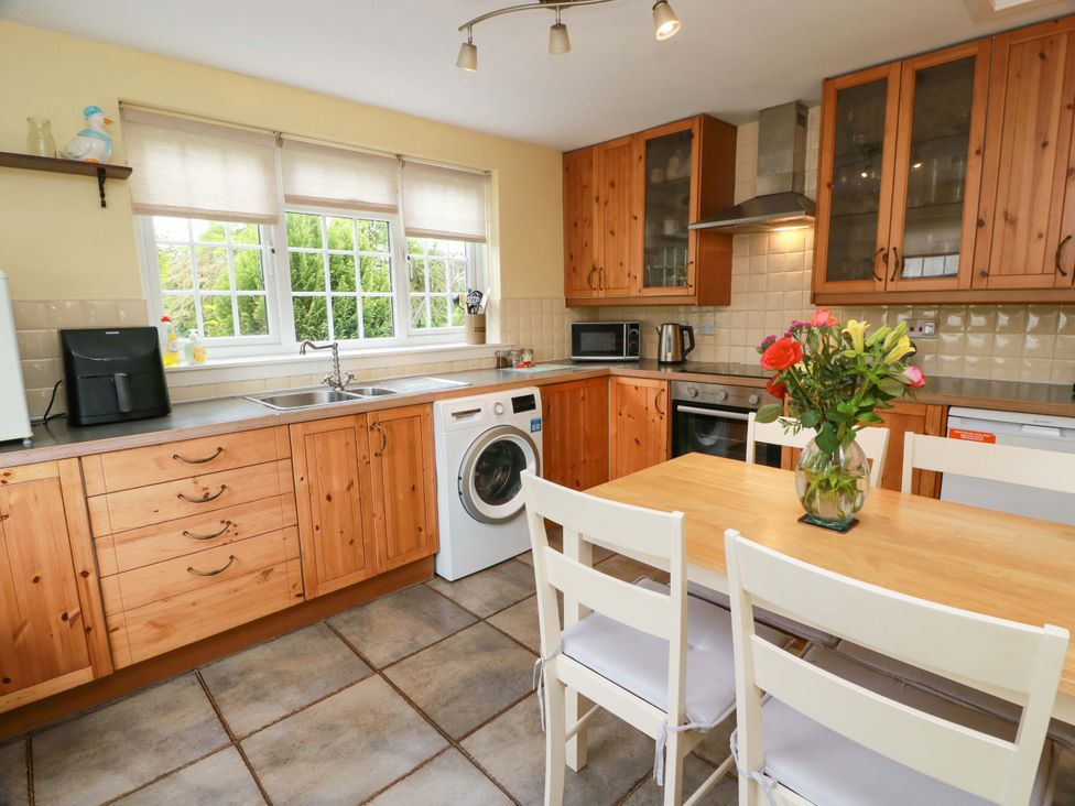 A kitchen with wooden cabinets and a dining table at Camphill in Kirkcudbright