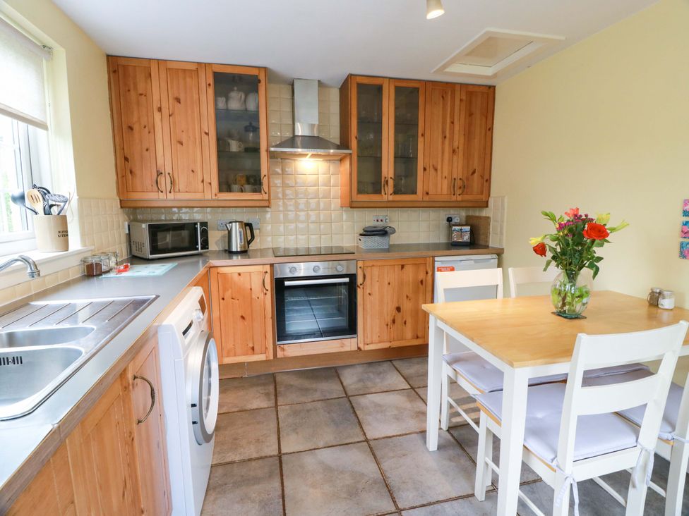 A kitchen with wooden cabinets and a table at Camphill in Kirkcudbright