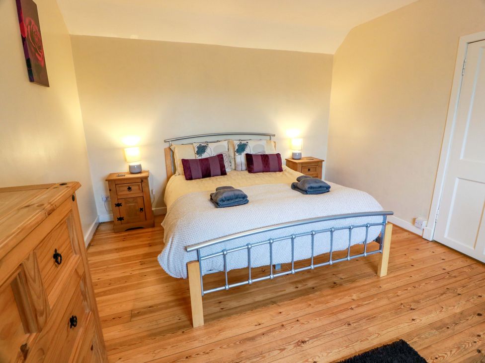 A bedroom with a double bed and wooden dresser at Camphill in Kirkcudbright
