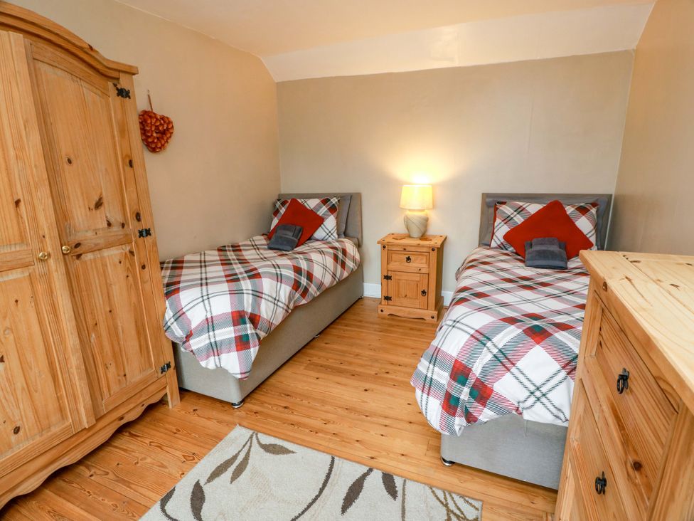 A bedroom with two single beds and a wardrobe at Camphill Kirkcudbright