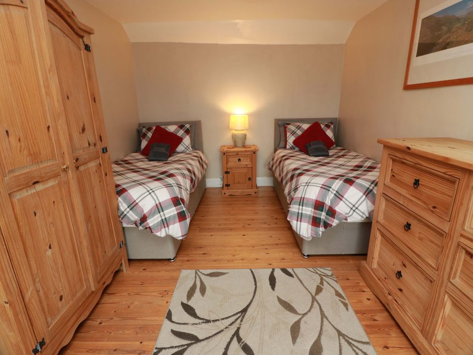 A bedroom with two beds and wooden furniture at Camphill in Kirkcudbright