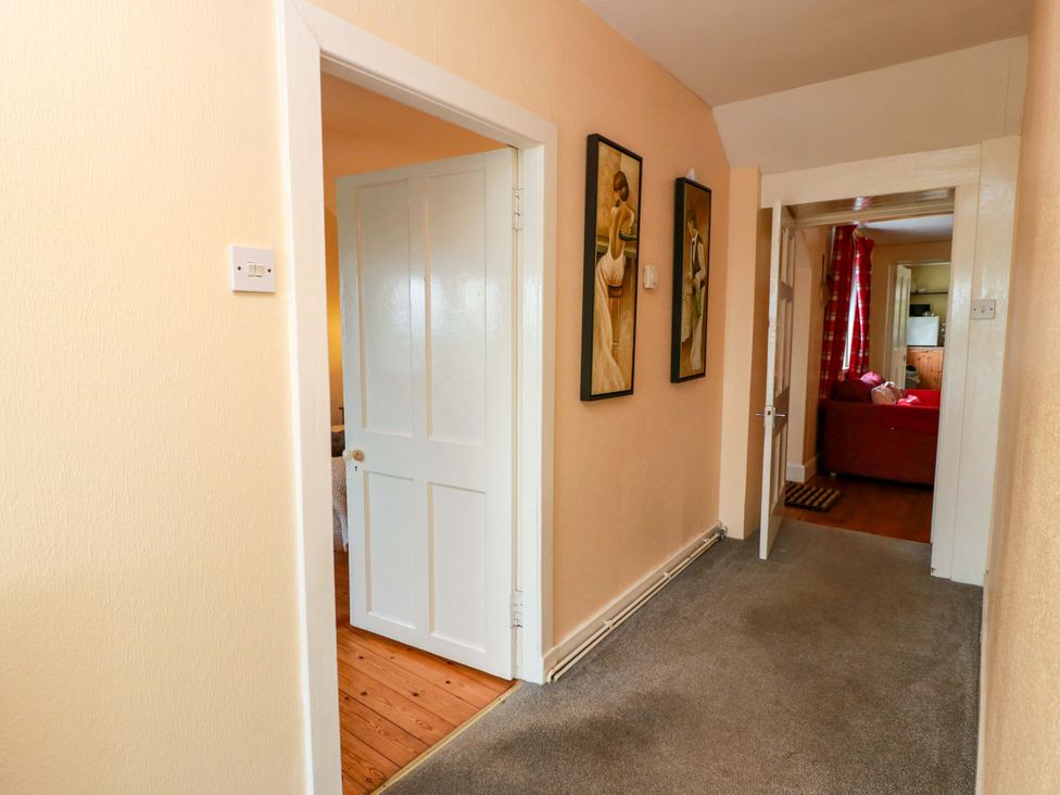 A hallway with paintings and doors leading to rooms at Camphill in Kirkcudbright