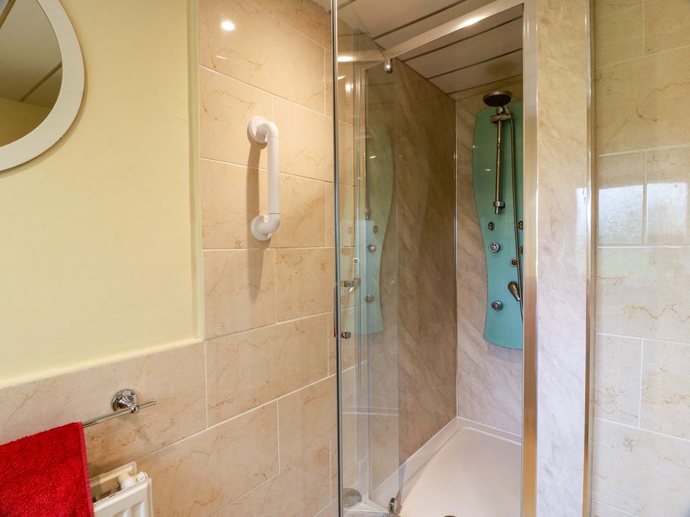 A shower with a glass door and a mirror in the bathroom at Camphill in Kirkcudbright