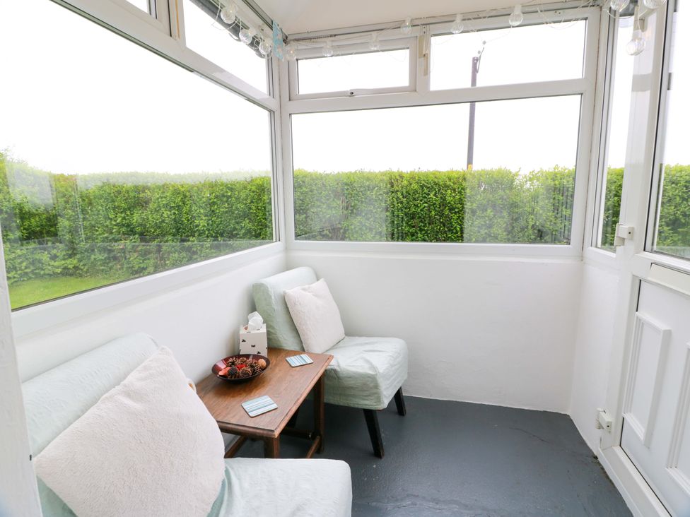 A conservatory with sofa and table at Camphill in Kirkcudbright