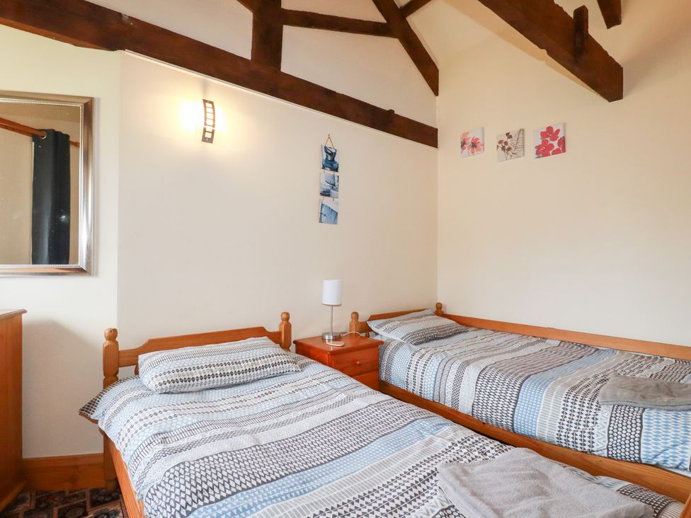 A bedroom with two beds and a mirror at Kingfisher Barn in East Taphouse