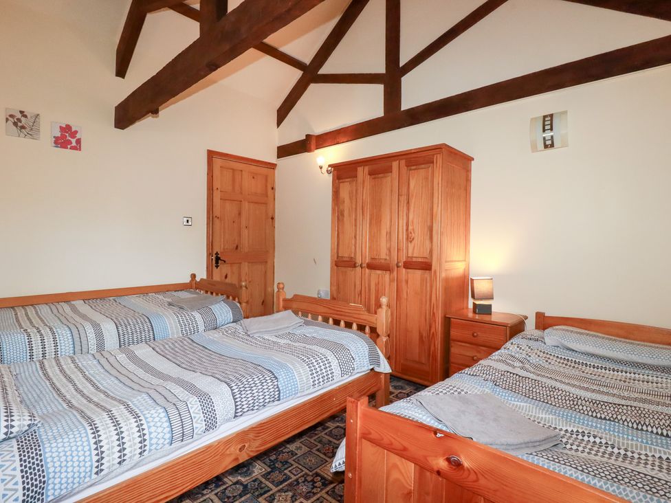 A bedroom with beds and a wardrobe at Kingfisher Barn East Taphouse
