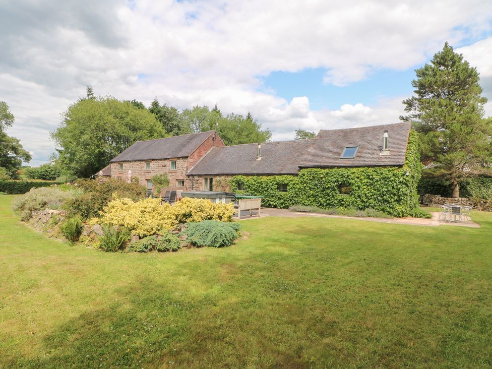 A garden with a building and seating area at Lee House Cottage in Cheddleton
