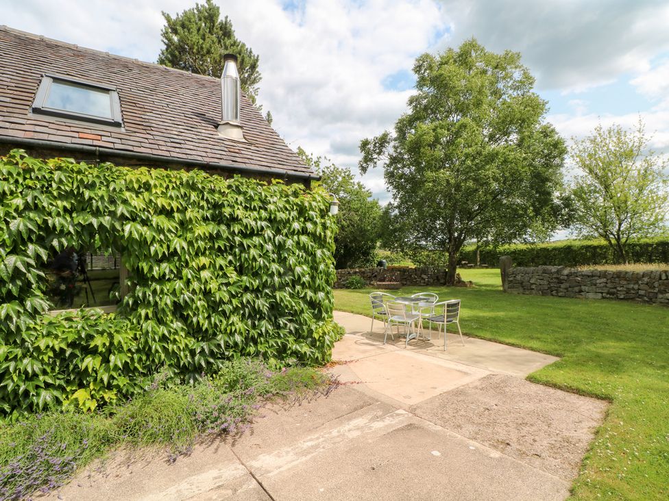 An outdoor area with a table and chairs next to a building at Lee House Cottage in Cheddleton