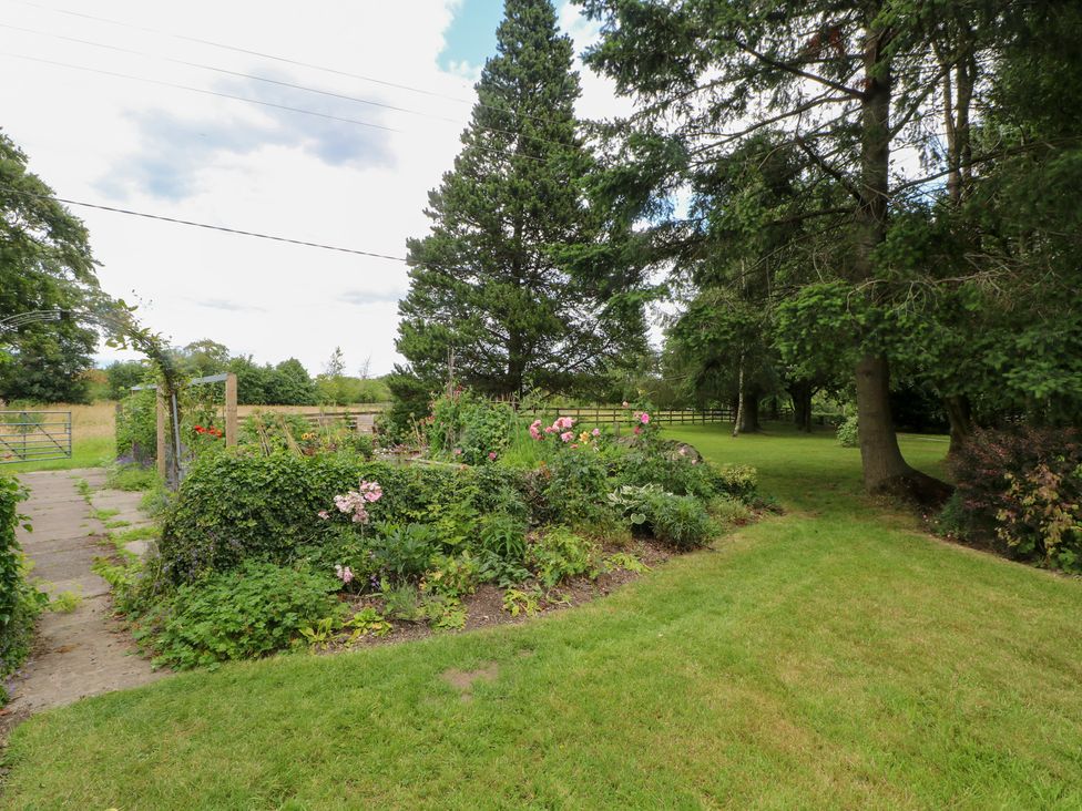 A garden with flowers and trees at Lee House Cottage in Cheddleton