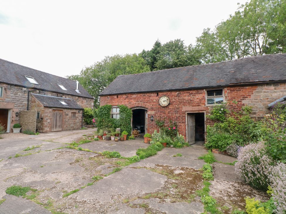 An outdoor view of a brick building with garden plants at Lee House Cottage in Cheddleton
