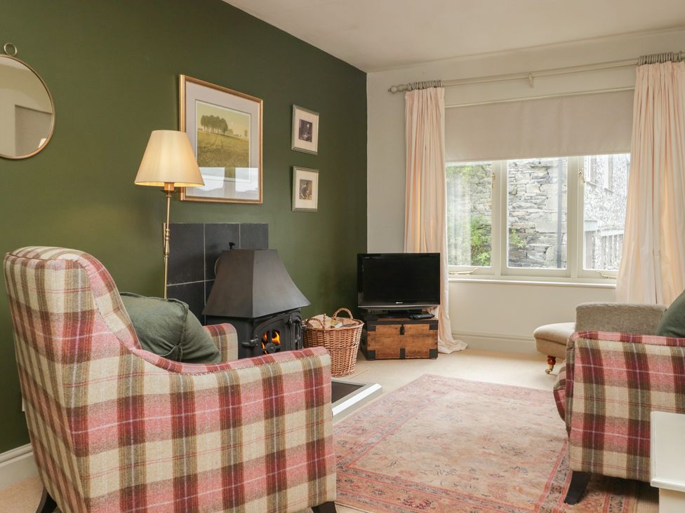 A living room with an armchair, fireplace, and television at Gable End in Coniston near Hawkshead