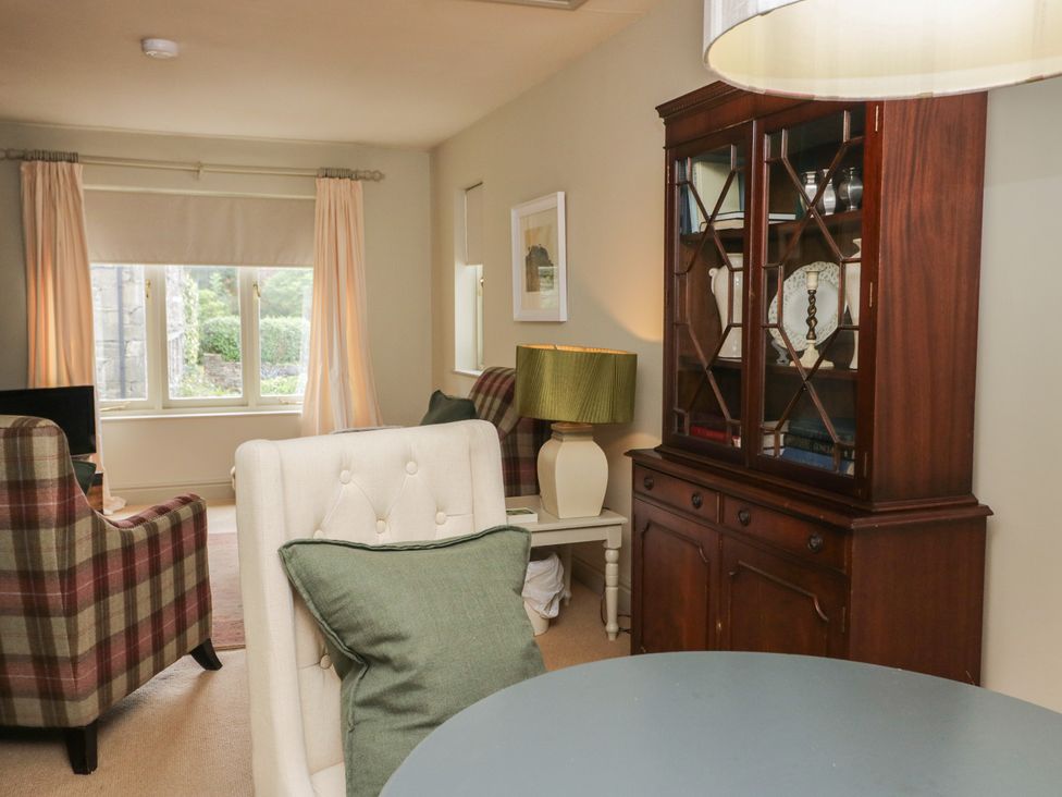 A living room with a chair, table and bookcase at Gable End in Coniston near Hawkshead